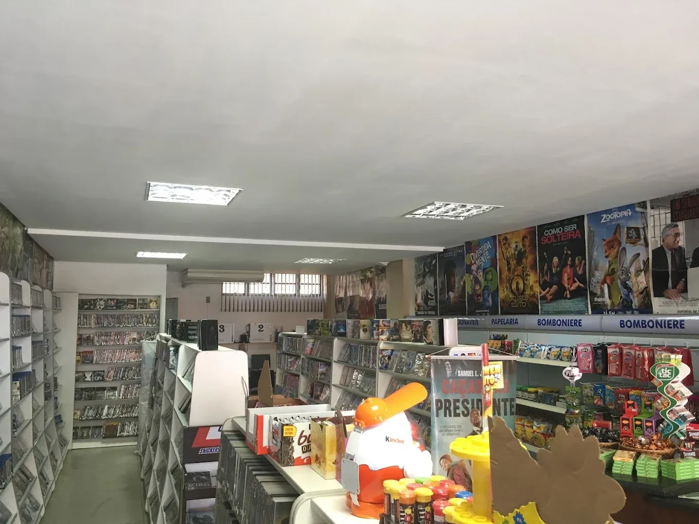 Interior da antiga videolocadora Lyons Store, com prateleiras de DVDs, cartazes de filmes e a bomboniere