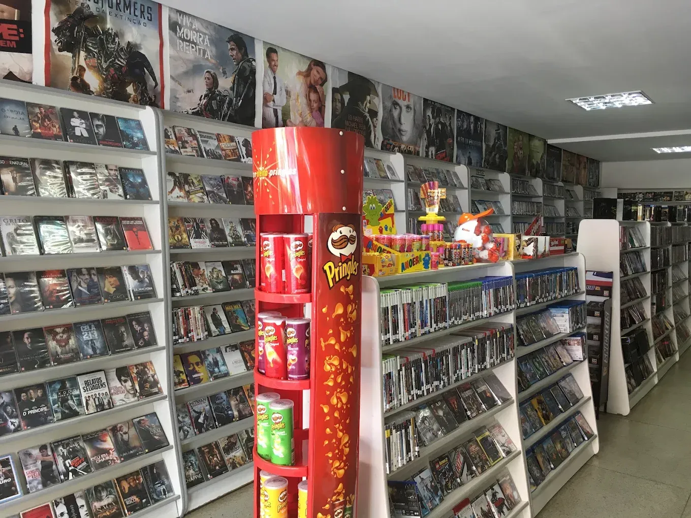 Corredor da antiga videolocadora Lyons Store, com estantes de DVDs e Blu-rays e cartazes de filmes no alto
